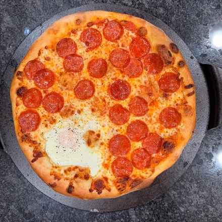 Rustic pepperoni pizza with a cracked egg baked into the center