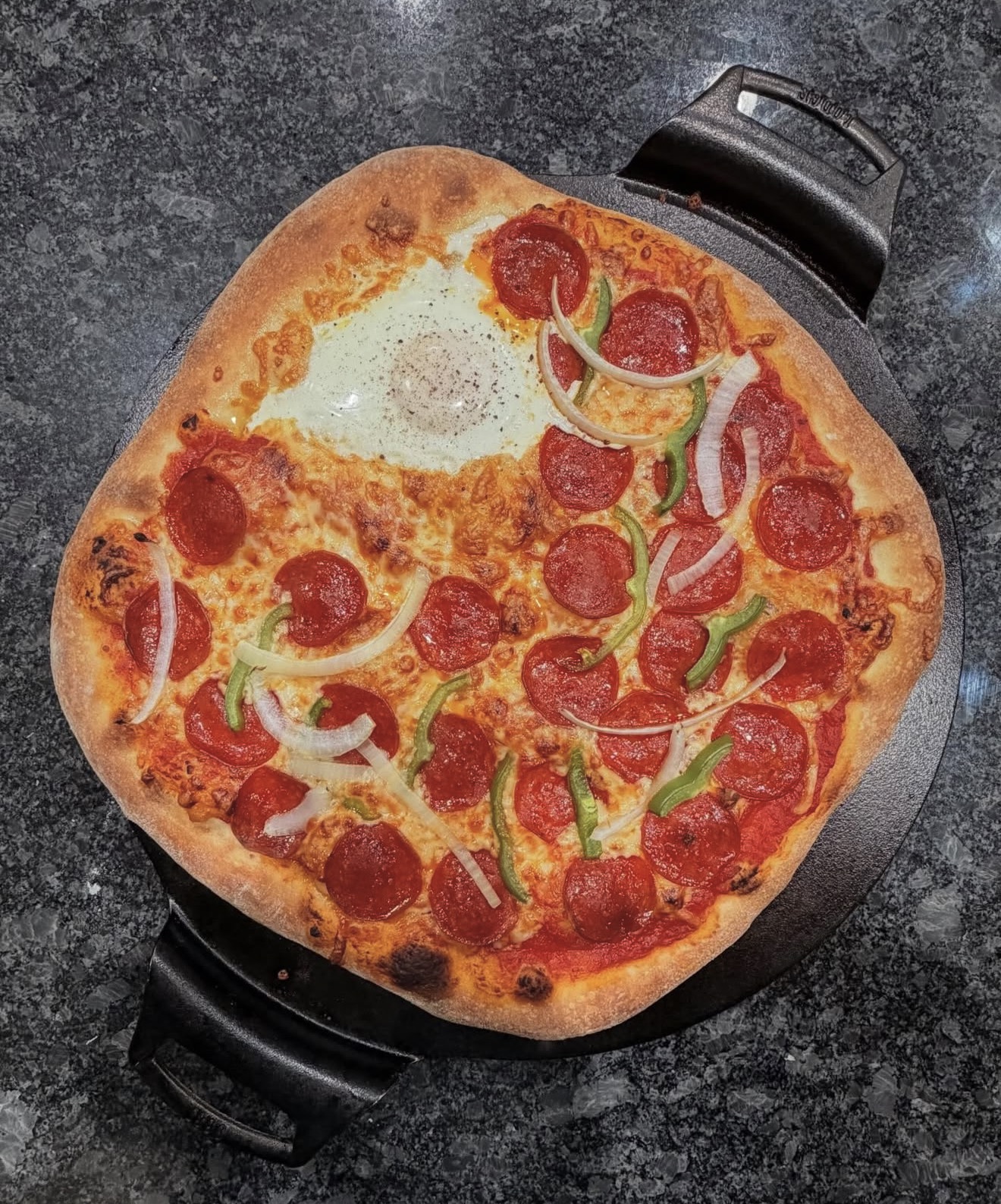 Pepperoni pizza with green peppers and onions in a cast iron pan