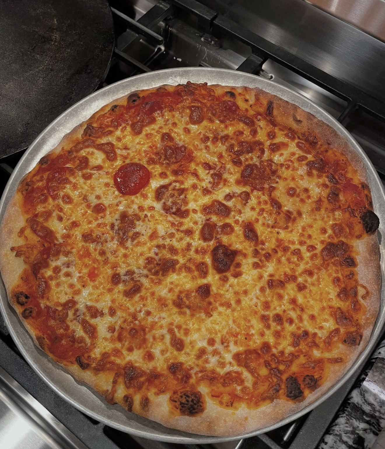 Bubbly pepperoni and cheese pizza fresh from the oven on a round pan